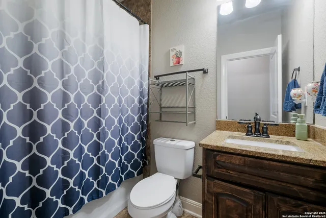 a bathroom with a granite countertop toilet and a sink