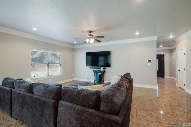 a living room with couches a flat screen tv and a chandelier