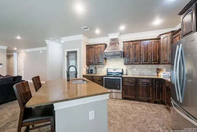 a kitchen with kitchen island granite countertop a table chairs microwave and refrigerator