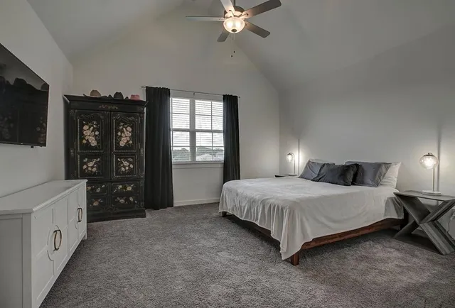a bedroom with a bed and a flat tv screen on dresser