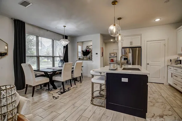a kitchen with a dining table chairs and refrigerator