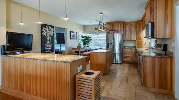 a kitchen with stainless steel appliances kitchen island granite countertop a sink dishwasher and a wooden cabinets