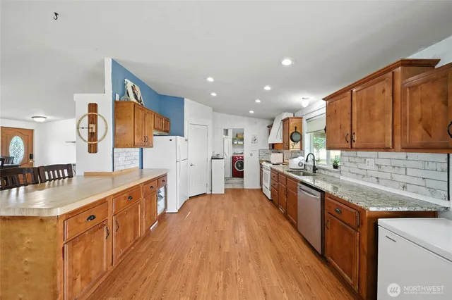a large kitchen with stainless steel appliances granite countertop a large counter top a stove and a sink