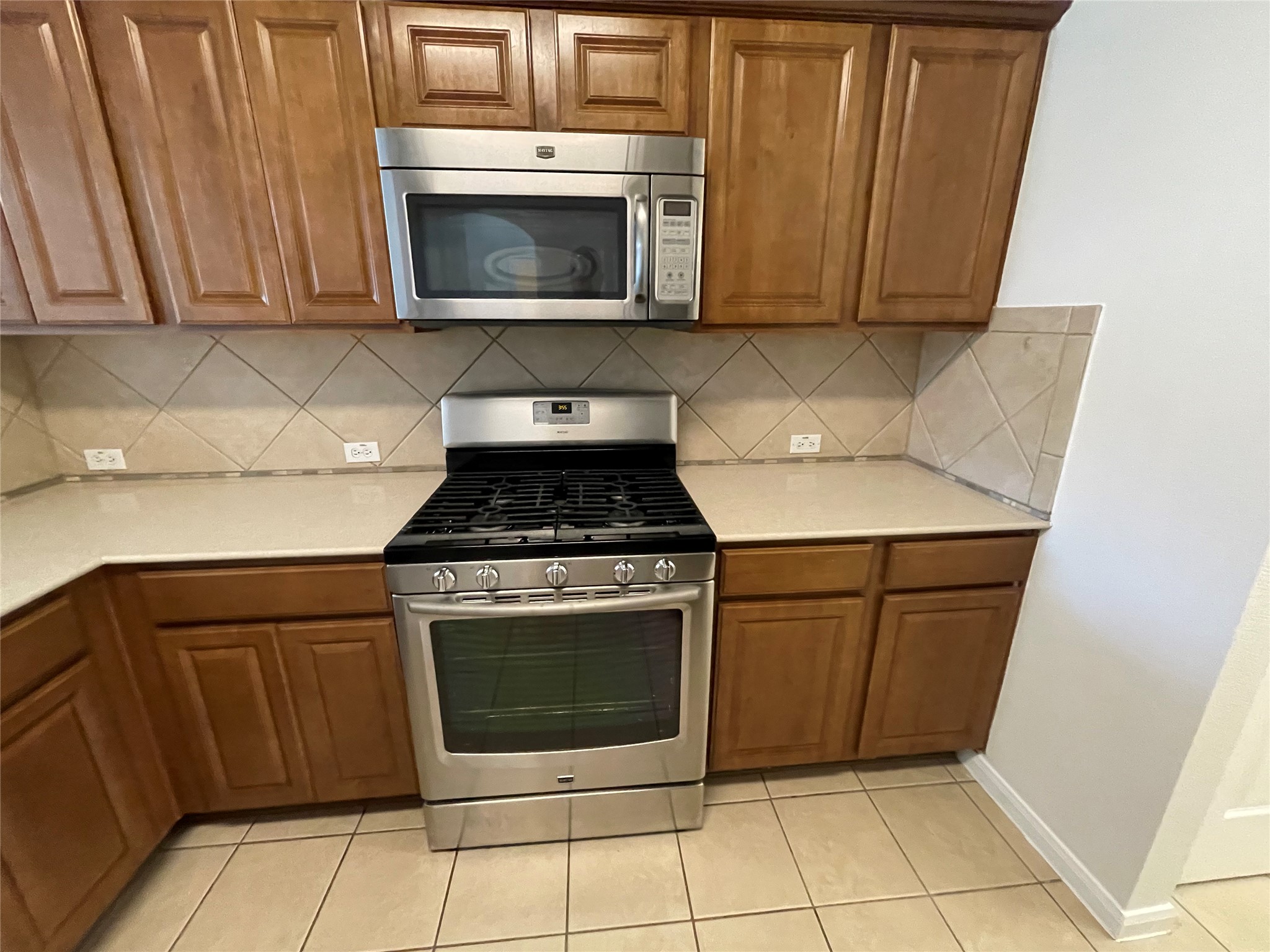 3517 Bronco Bend Loop Austin, TX 78744 - Photo 11 of 39 Kitchen with stainless steel appliances, wood finish cabinets, light tile patterned floors, and tasteful backsplash