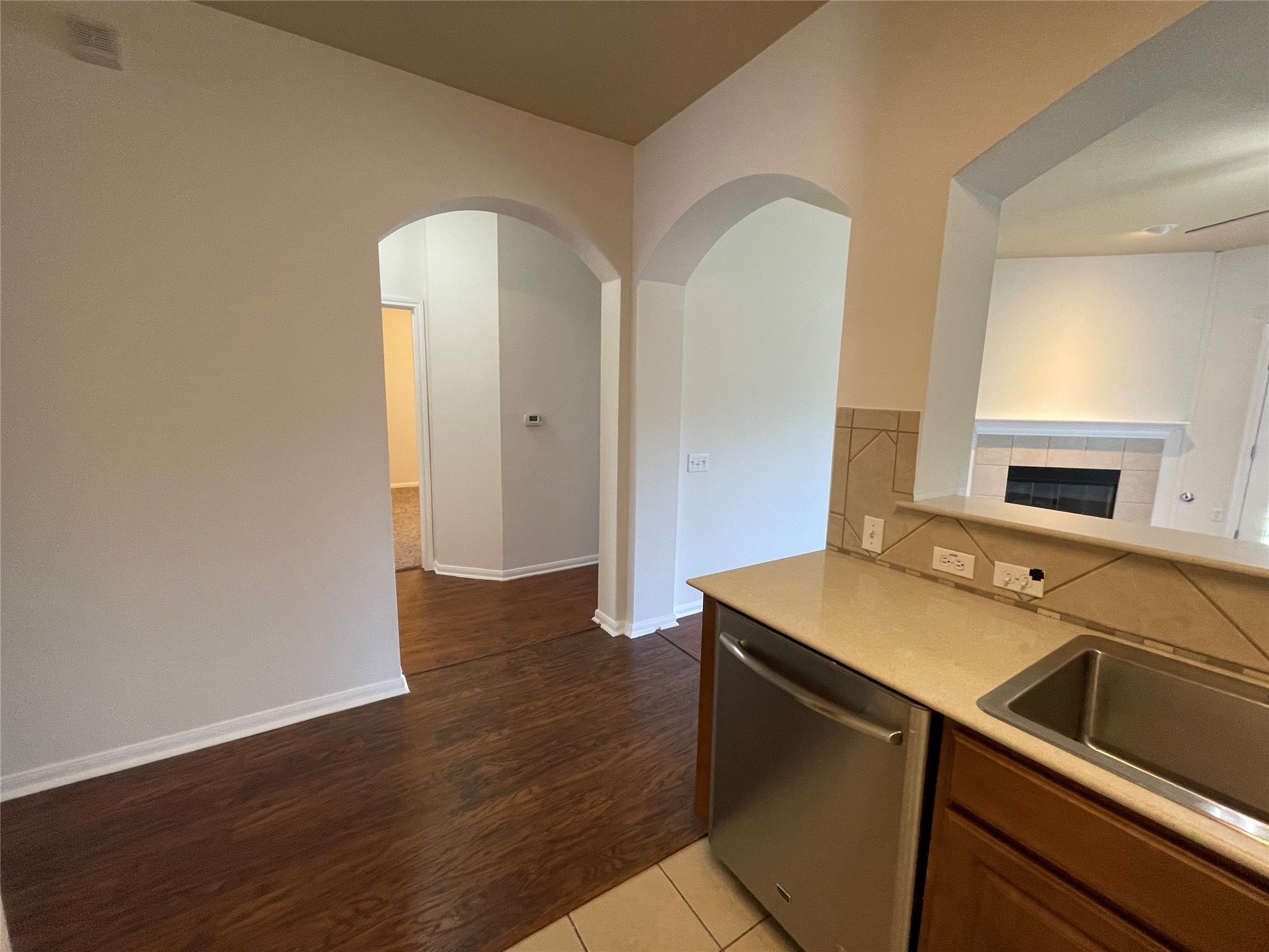 3517 Bronco Bend Loop Austin, TX 78744 - Photo 12 of 39 Kitchen with light countertops, dishwasher, light tile patterned floors, arched walkways, and a tile fireplace