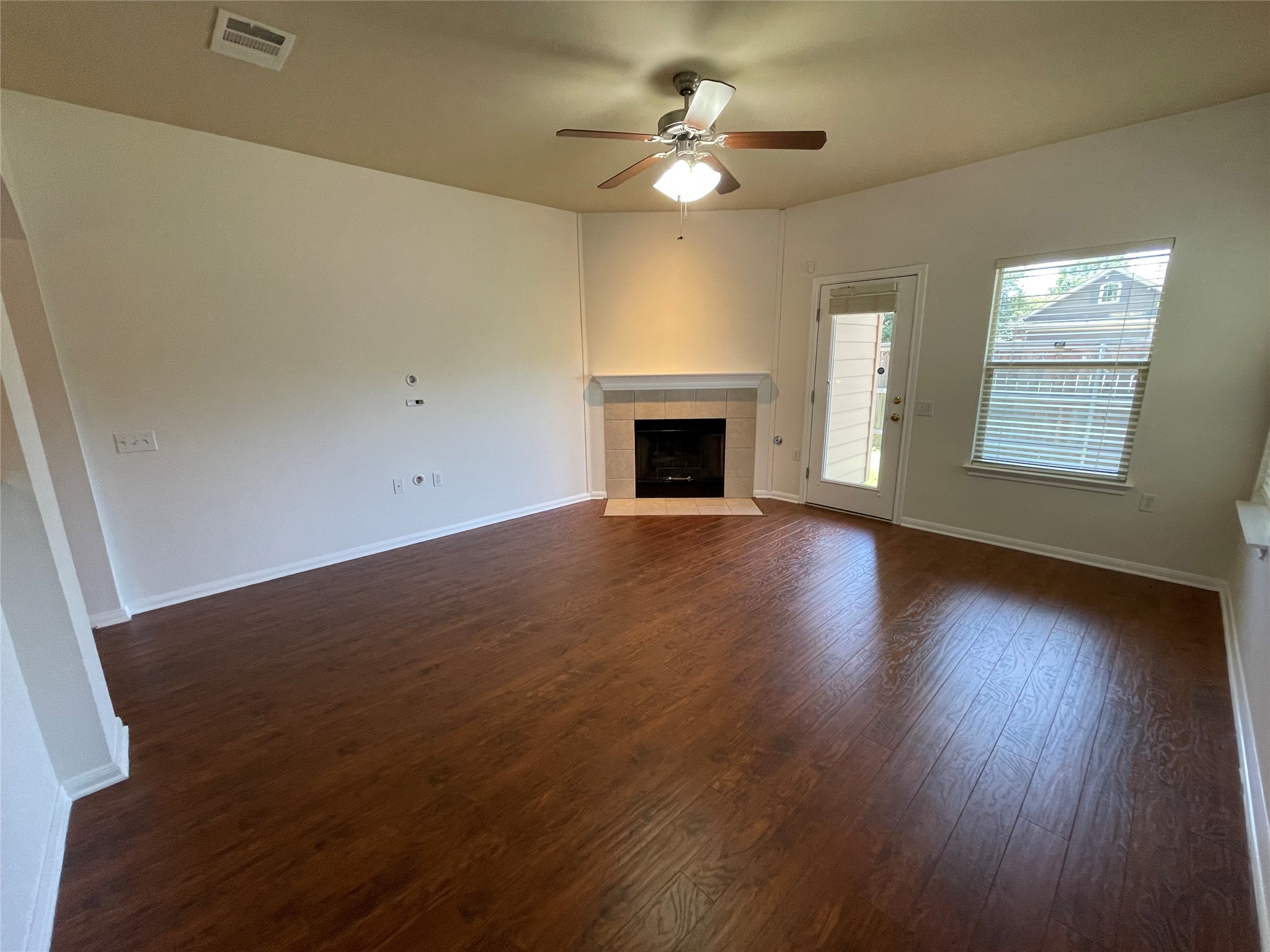 3517 Bronco Bend Loop Austin, TX 78744 - Photo 16 of 39 Unfurnished living room with dark wood-style floors, ceiling fan, and a tiled fireplace