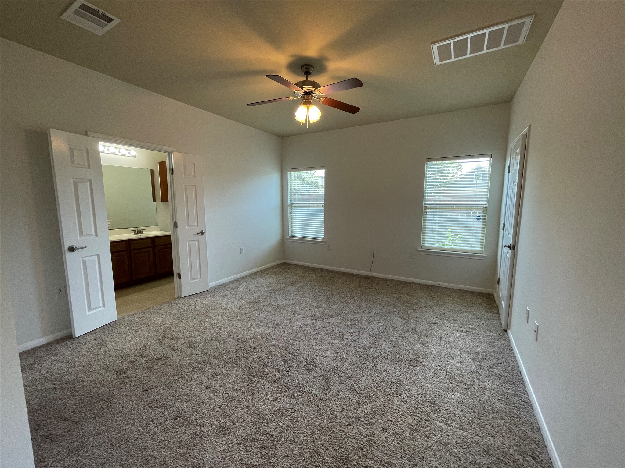 3517 Bronco Bend Loop Austin, TX 78744 - Photo 19 of 39 Unfurnished bedroom with light carpet, connected bathroom, and a ceiling fan