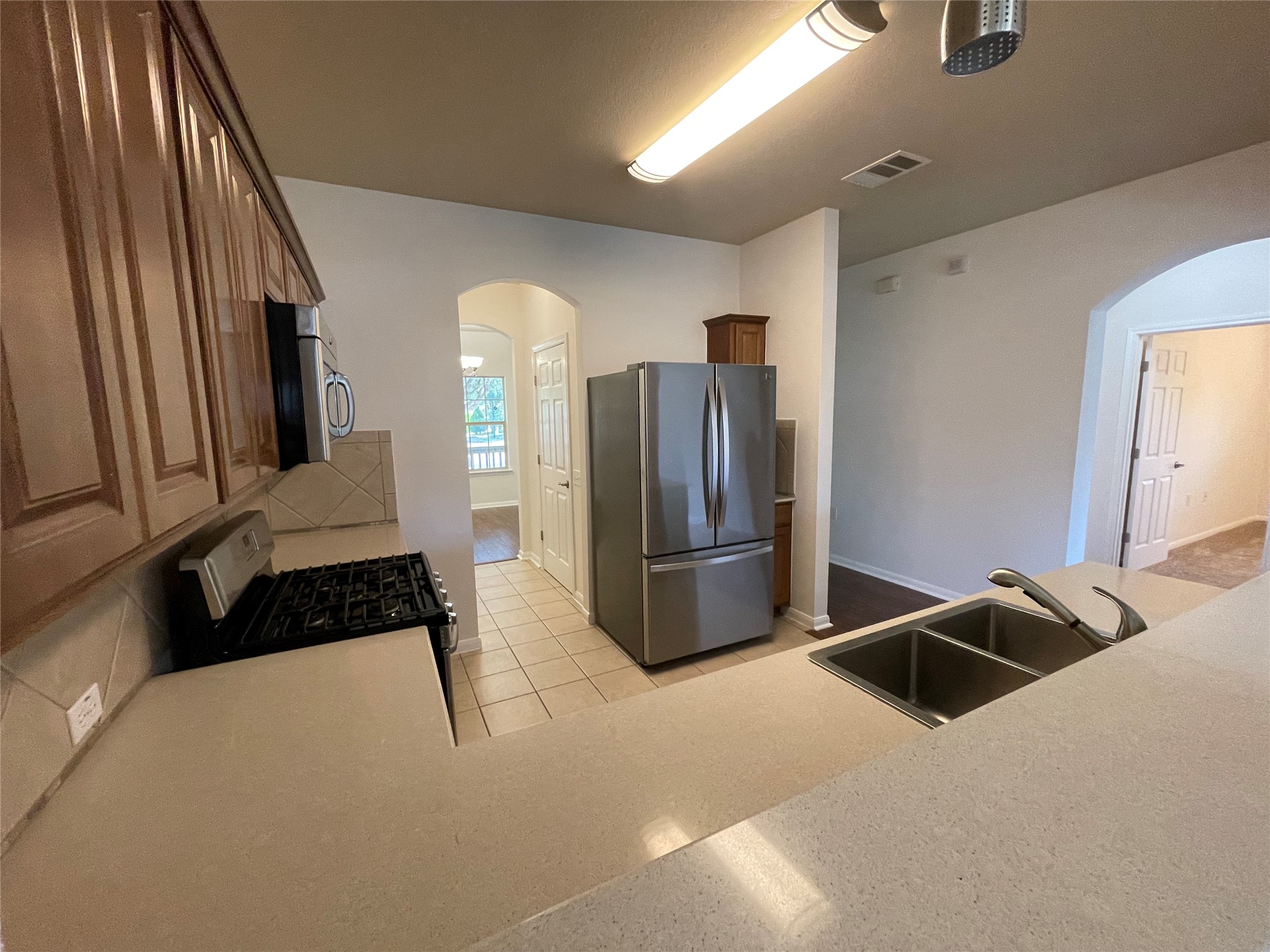 3517 Bronco Bend Loop Austin, TX 78744 - Photo 7 of 39 Kitchen with arched walkways, stainless steel appliances, light countertops, and light tile patterned flooring