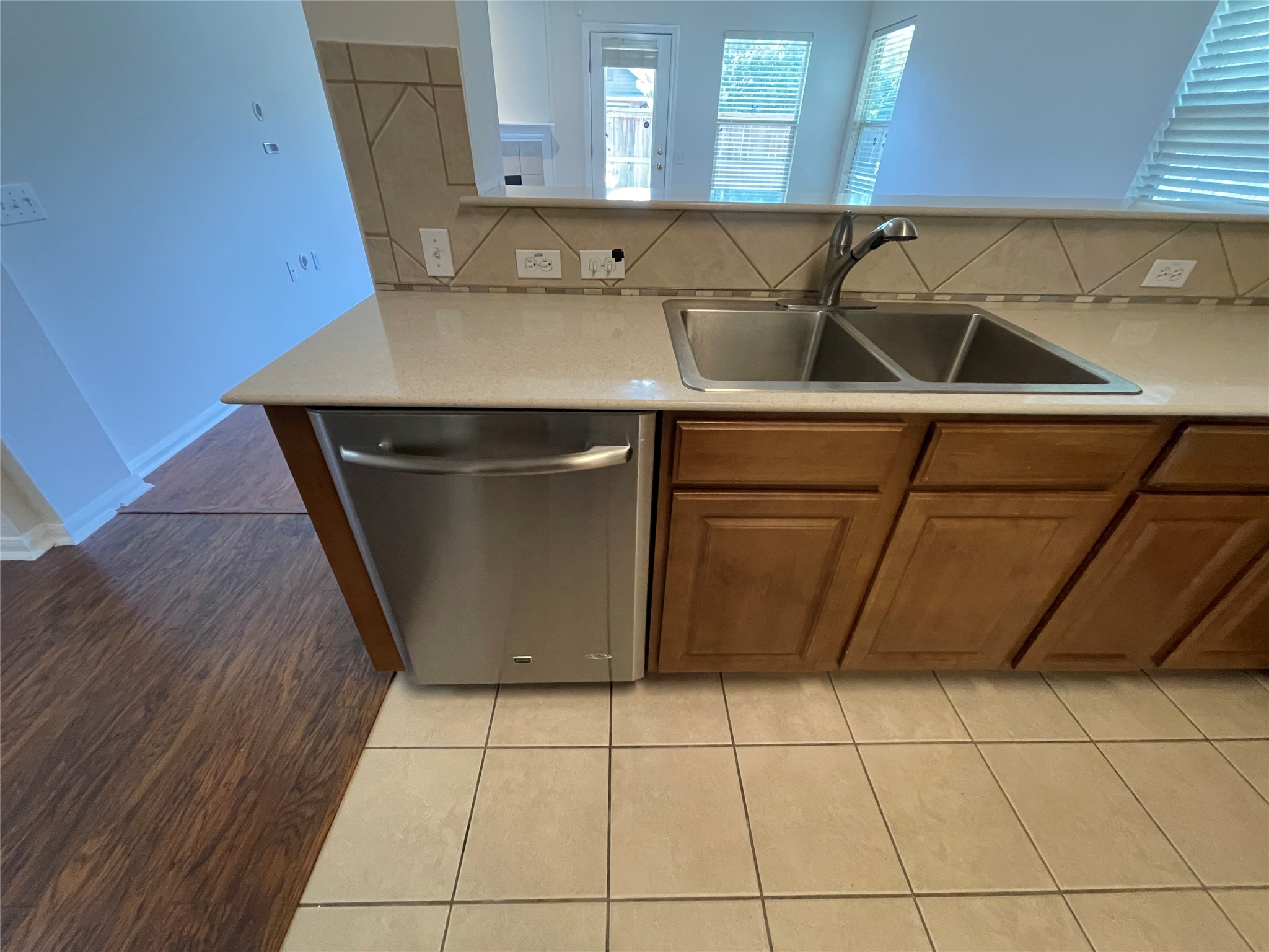 3517 Bronco Bend Loop Austin, TX 78744 - Photo 9 of 39 Kitchen with dishwasher, wood finish cabinetry, decorative backsplash, and light tile patterned floors