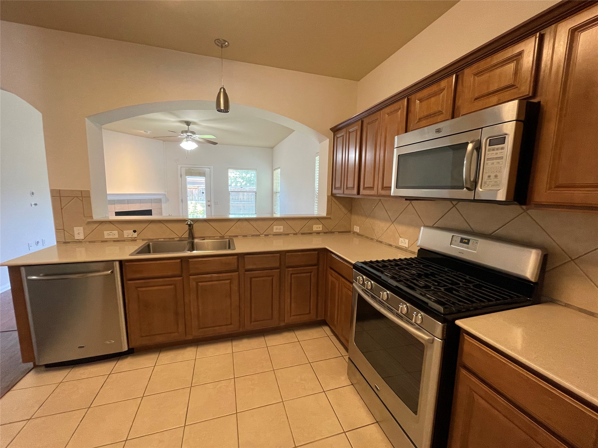 3517 Bronco Bend Loop Austin, TX 78744 - Photo 10 of 39 Kitchen with stainless steel appliances, wood finish cabinetry, light tile patterned floors, and a ceiling fan