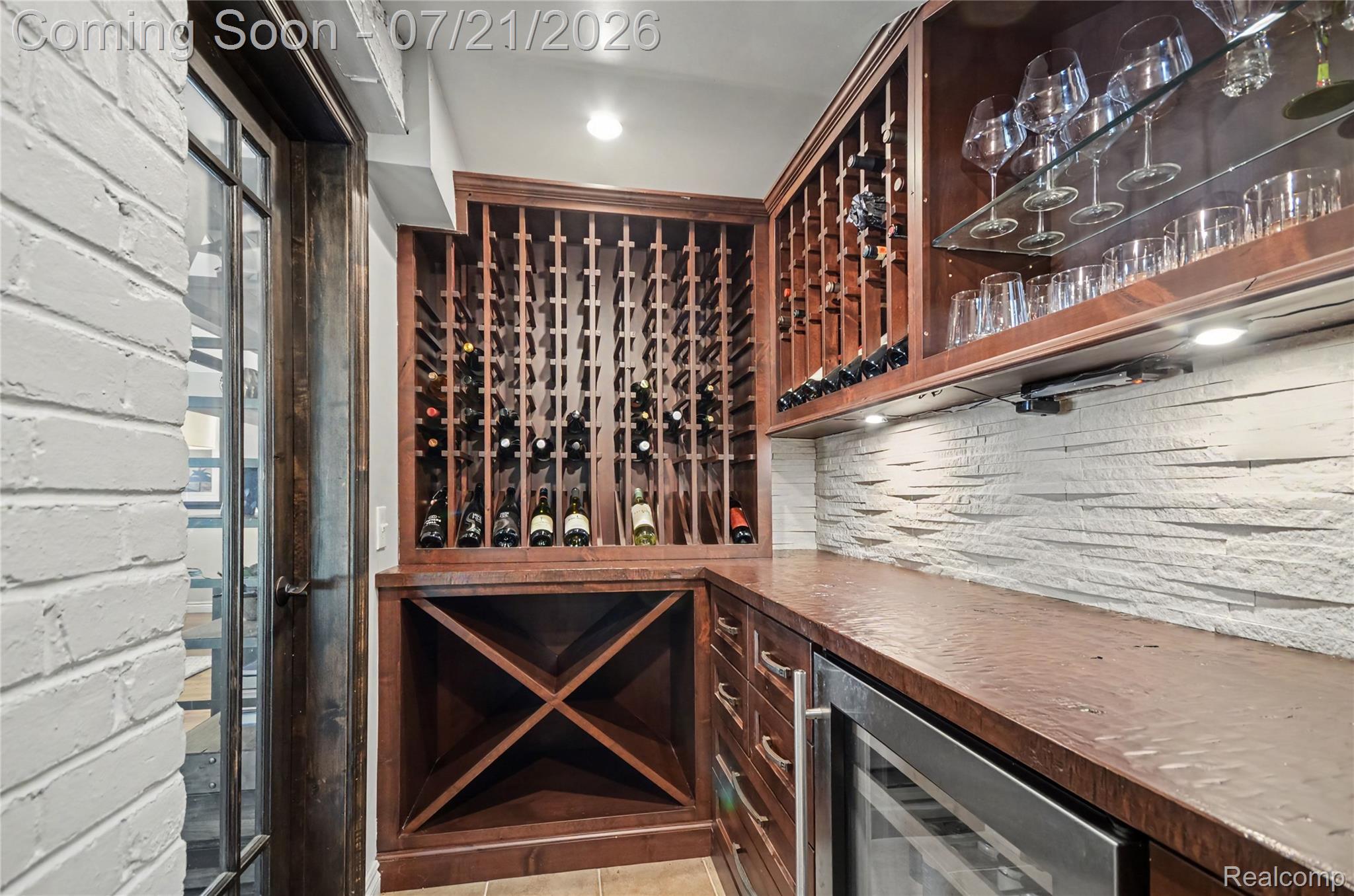 3780 Squirrel Road Bloomfield Hills, MI 48304 - Photo 12 of 59 Dedicated wine cellar featuring extensive wooden bottle storage, built-in beverage refrigerator, wood-finish countertop, textured stone backsplash, and glass display shelving