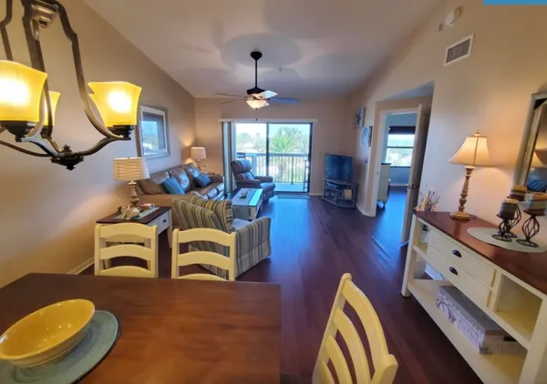 a living room with dining table and a chandelier