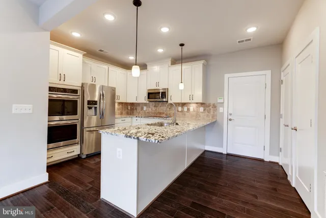 a kitchen with kitchen island a stove a refrigerator and a oven with wooden floor