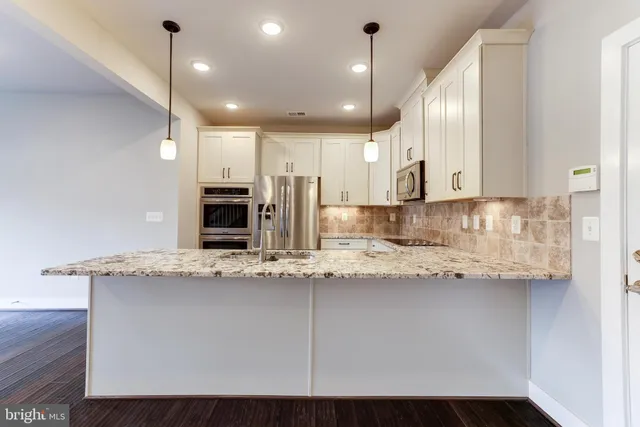 a kitchen with kitchen island granite countertop a sink cabinets and stainless steel appliances