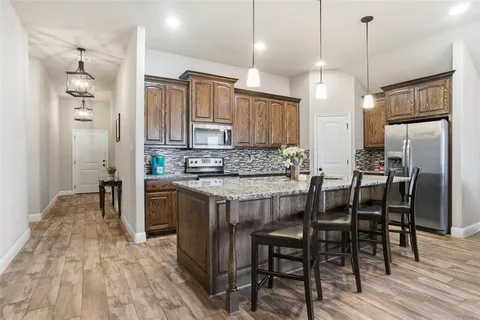 a kitchen with kitchen island granite countertop a table chairs a sink refrigerator and cabinets