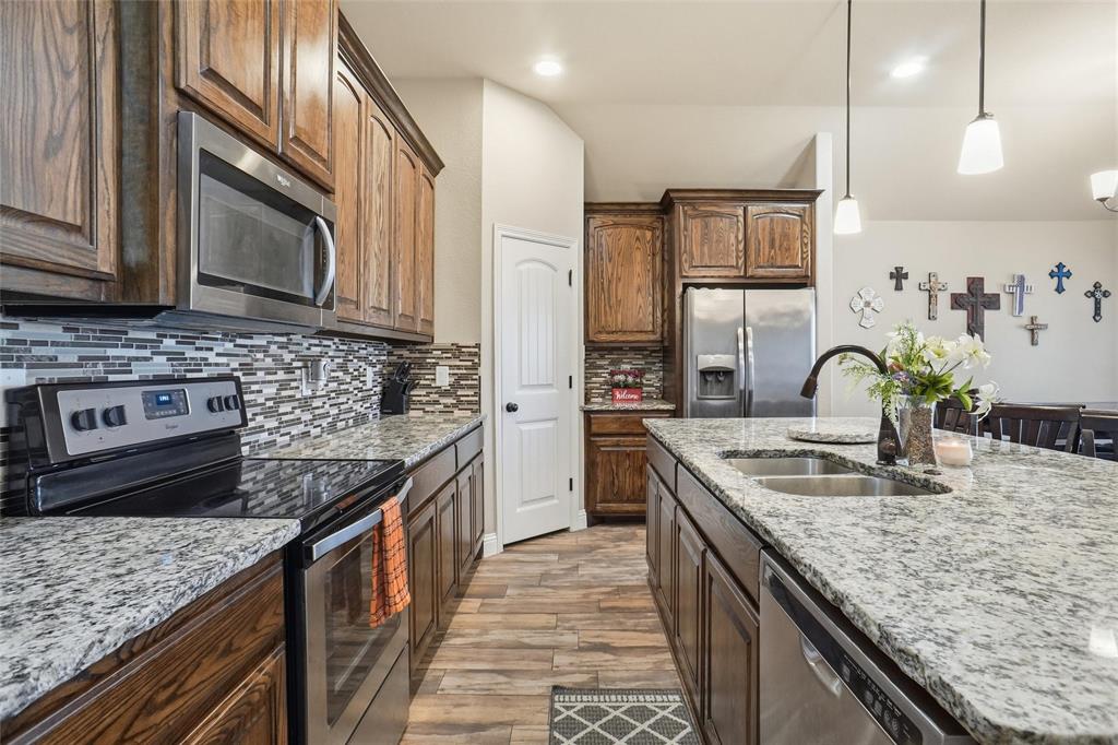 206 McKittrick Lane Godley, TX 76044 - Photo 6 of 28 Kitchen with appliances with stainless steel finishes, hanging light fixtures, light stone counters, decorative backsplash, and recessed lighting