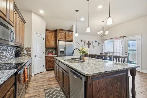 a kitchen with granite countertop kitchen island stainless steel appliances a sink stove and cabinets