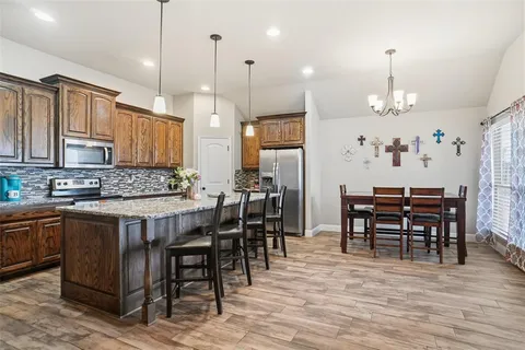 a view of a a dining table chairs wooden floor and kitchen view