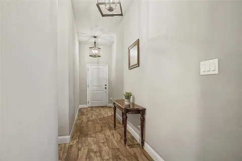 a view of a hallway with wooden floor and a bathroom