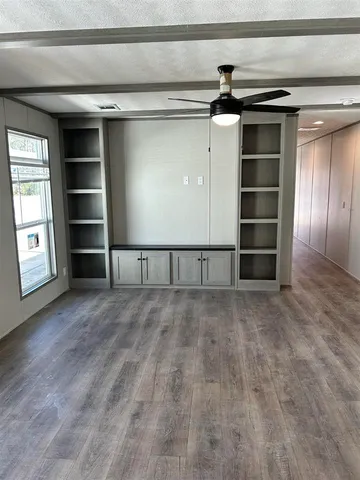 a view of an empty room with window and wooden floor