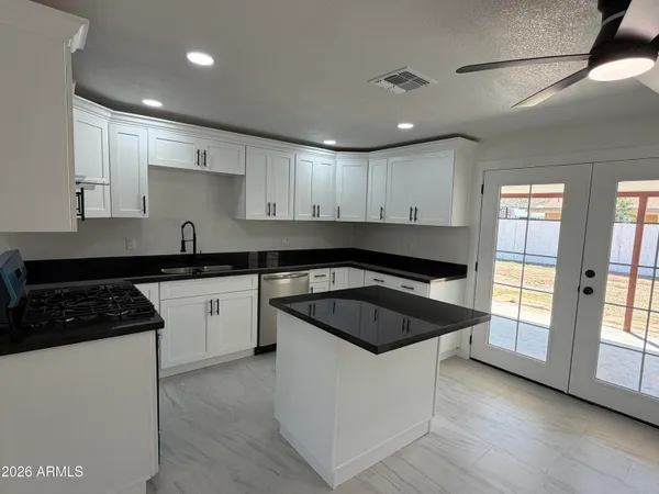 a kitchen with a sink a stove a refrigerator a white cabinets and wooden floor