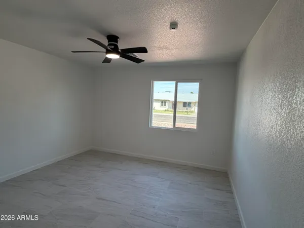 an empty room with a window and a fan