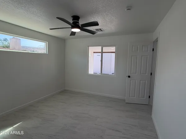 an empty room with windows and fan