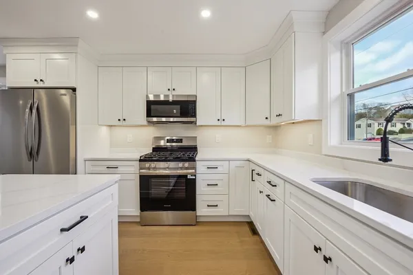 a kitchen with granite countertop white cabinets and stainless steel appliances