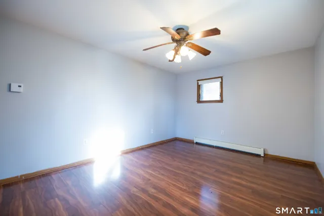 a view of an empty room with wooden floor and a window