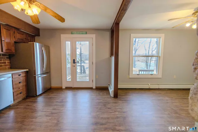 a kitchen with stainless steel appliances granite countertop a refrigerator a sink dishwasher a stove and white countertops with wooden floor