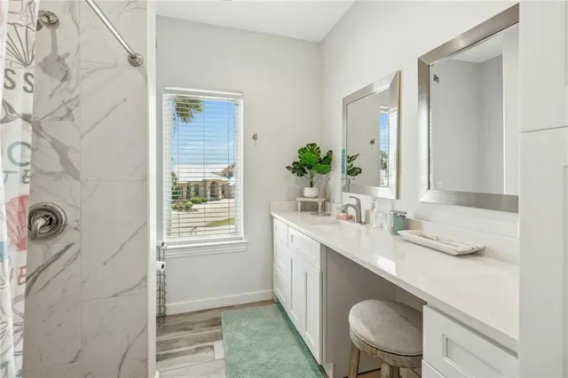 a en suite bathroom with a granite countertop sink a mirror and shower