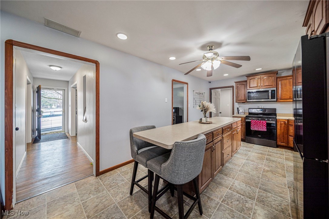 6600 Reynolds Road Mentor, OH 44060 - Photo 12 of 35 Kitchen featuring a kitchen island, ceiling fan, appliances with stainless steel finishes, and a kitchen bar