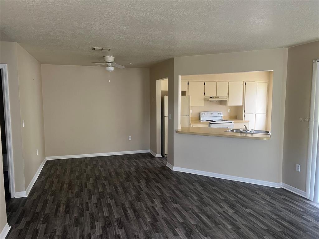 7266 Pond Circle Spring Hill, FL 34606 - Photo 15 of 15 an empty room with wooden floor and kitchen view