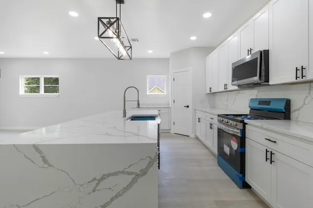 a kitchen with stainless steel appliances granite countertop a sink a stove top oven a counter space and cabinets