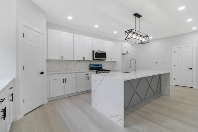 a kitchen with kitchen island granite countertop stainless steel appliances a stove a sink and a refrigerator