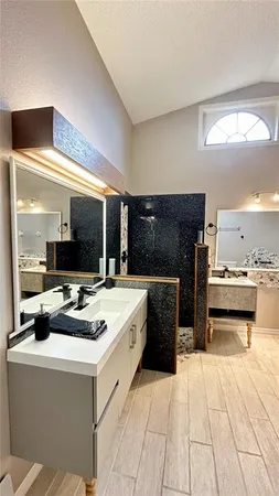 a spacious bathroom with a granite countertop sink a large mirror and a bathtub