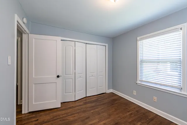 a view of an empty room with closet and a window