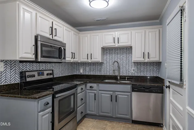 a kitchen with granite countertop white cabinets and black appliances
