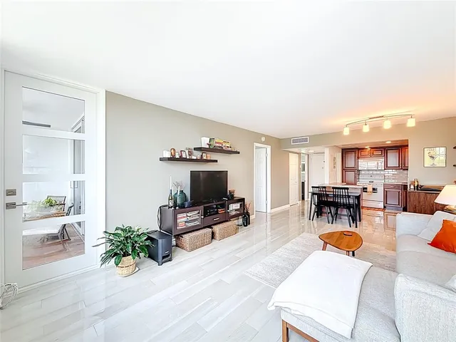 a living room with furniture a couch and potted plants with wooden floor