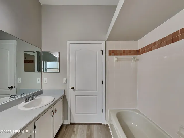 a bathroom with a tub sink and mirror