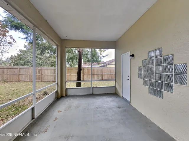 a view of an empty room with wooden floor and windows