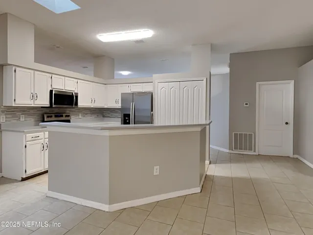 a kitchen with white cabinets a sink and appliances