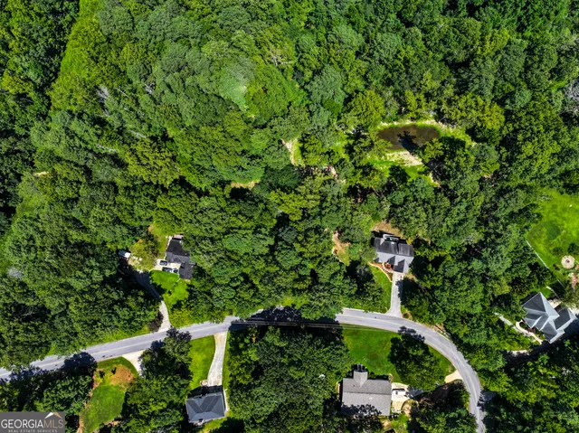an aerial view of residential house with outdoor space and trees all around