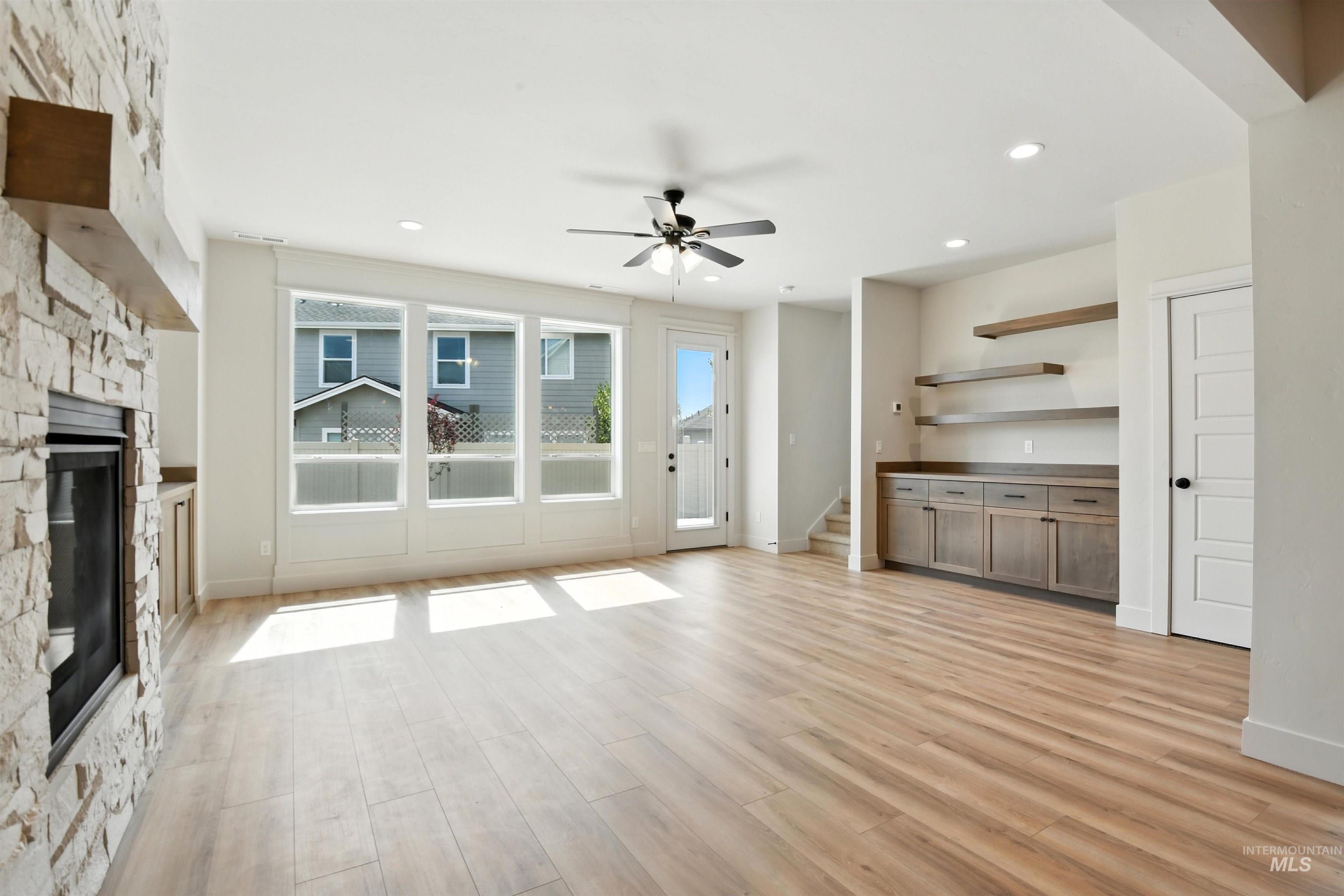 3521 South El Rio Avenue Boise, ID 83709 - Photo 21 of 38 Unfurnished living room with a stone fireplace, a ceiling fan, light wood-style flooring, stairway, and recessed lighting