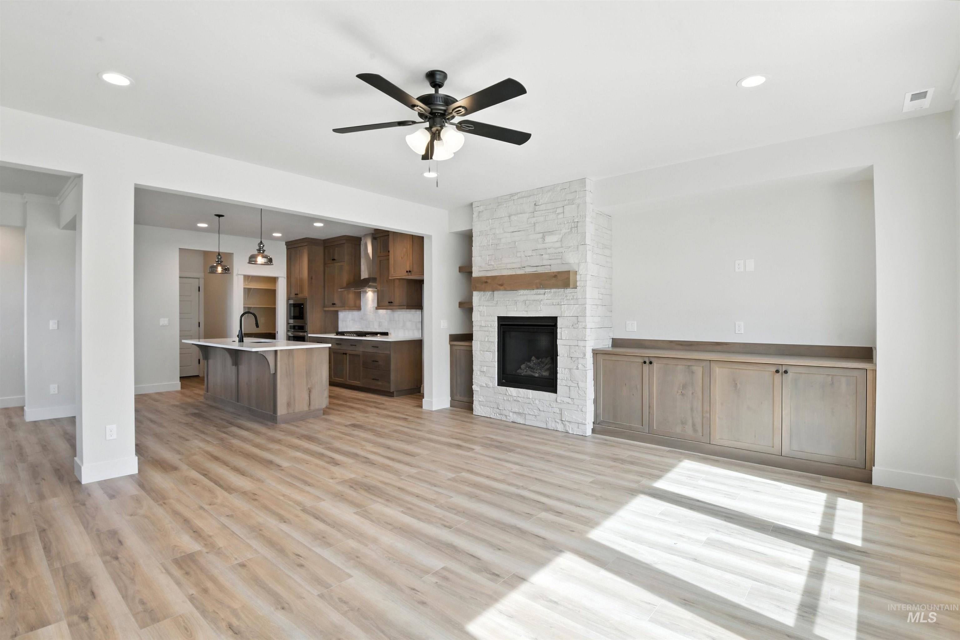 3521 South El Rio Avenue Boise, ID 83709 - Photo 23 of 38 Unfurnished living room featuring ceiling fan, a fireplace, light wood-style flooring, and recessed lighting