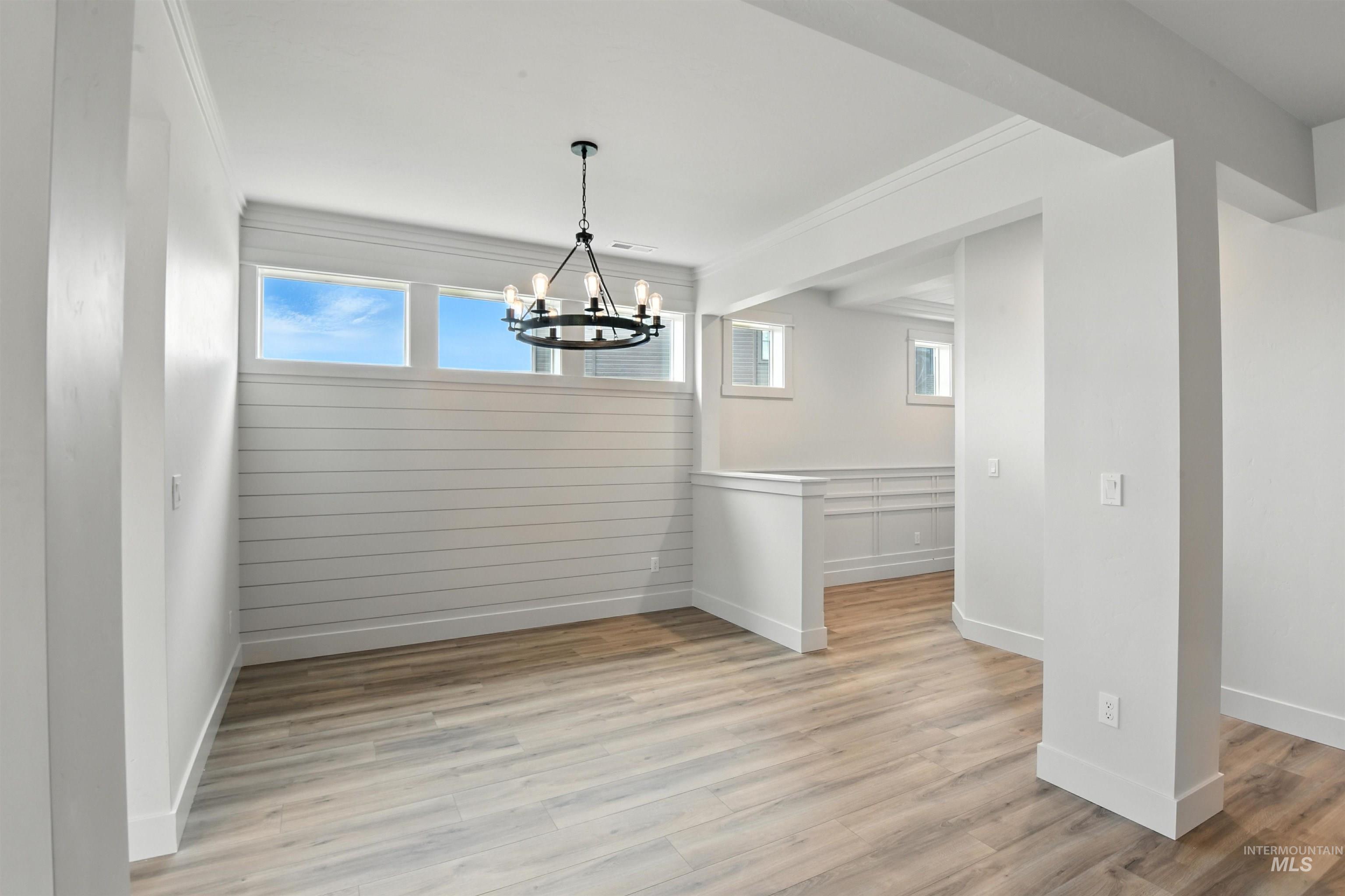3521 South El Rio Avenue Boise, ID 83709 - Photo 9 of 38 Unfurnished dining area with a chandelier, light wood-style floors, and ornamental molding