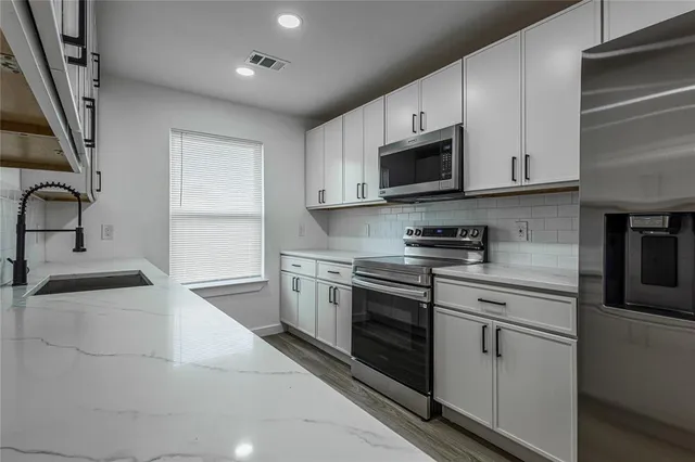 a kitchen with stainless steel appliances granite countertop a sink and a stove top oven