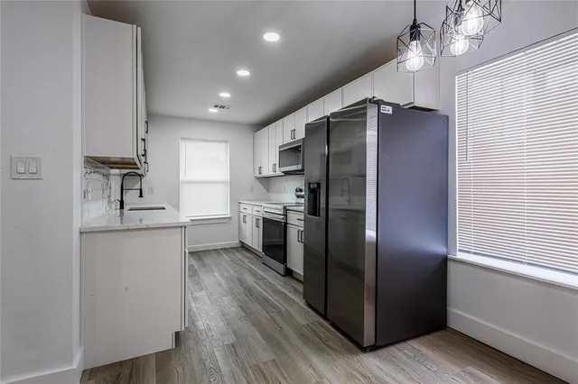 a kitchen with kitchen island granite countertop stainless steel appliances cabinets a sink and a window