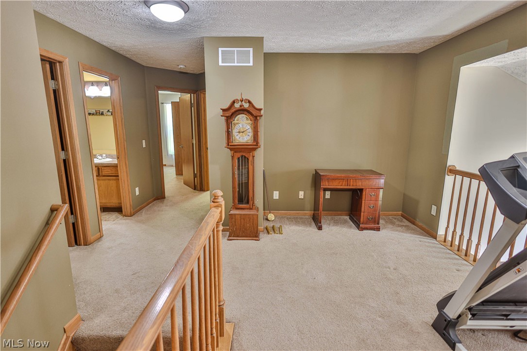 11154 Johnsford Road Southwest Beach City, OH 44608 - Photo 45 of 50 Carpeted hallway with multiple wood-trimmed doorways, a wooden railing, and a ceiling light fixture