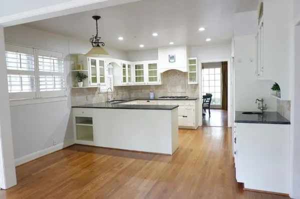 a kitchen with stainless steel appliances granite countertop a sink a stove a refrigerator and island with wooden floor